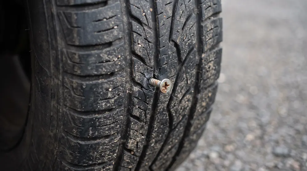 A screw embedded in a car tyre's tread causing a puncture